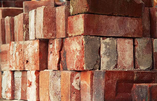 Red clay bricks loosley stacked and ready for use on a construction site.